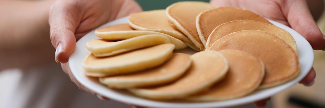 Woman holding plate with tasty fresh homemade pancakes