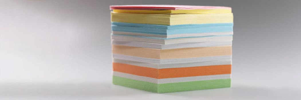 Uneven stack of sticky post it notes on grey surface, bunch of clean papers