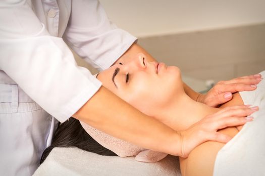 Young caucasian woman with closed eyes getting a chest massage in a beauty clinic.