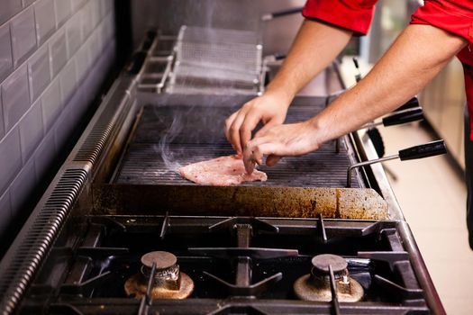 Chef making chicken brerast on restaurant grill