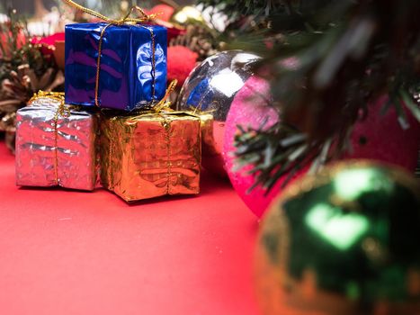 Christmas gift boxes wrapped in different colors under christmas tree on red background