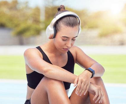 Sport runner woman listening to music on break from training, exercise and fitness workout. Tired athlete rest to recover from pain, prevent muscle injury and physical exhaustion or medical emergency