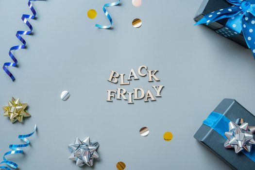 Black friday text with gifts and festive tinsel flat lay
