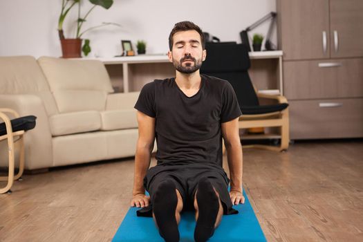 Young man sitting on the floor doing Paschimottanasana yoga pose