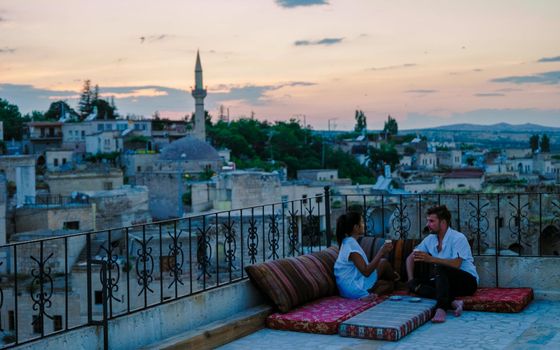 Couple with drink on rooftop of an cave house historical village of Ayvali Goreme Cappadocia Turkey