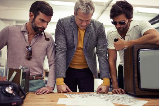 Well, here are our choices...Three designers clad in retro 70s wear working on a project together.