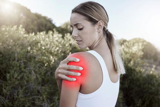 Fitness, woman and shoulder injury, pain or joint inflammation holding sore area in nature outdoors. Injured female suffering in painful muscle tension from training, workout or exercise accident