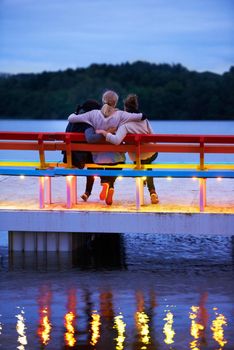 Moments of romance. Rearview shot of three women sitting on a bench on a pier over a lake.