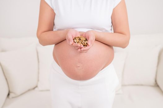 Pregnant woman holding a handful of walnuts.