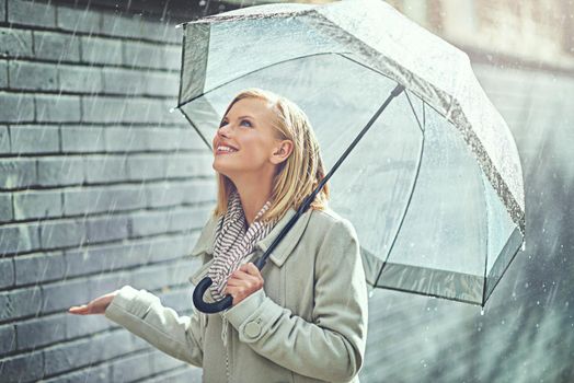 Its raining happiness. an attractive young woman walking in the rain.