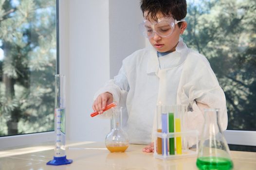 Elementary student boy conducting a chemical experiment, holding test tube in hands in science class .Education concept