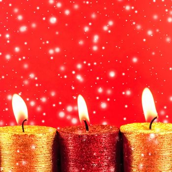 Christmas candles and shiny snow on red background, holiday season decoration