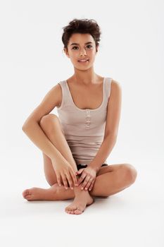 Casual and beautiful. A young woman sitting on the floor in a tank top.