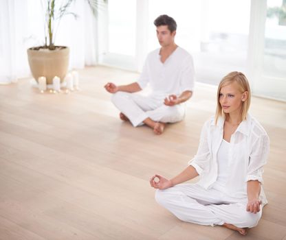 On their way to enlightenment...Two people sitting in the lotus position in a yoga studio