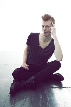 Dark style. A young man with a red mohawk posing in a black t-shirt and skinny jeans.