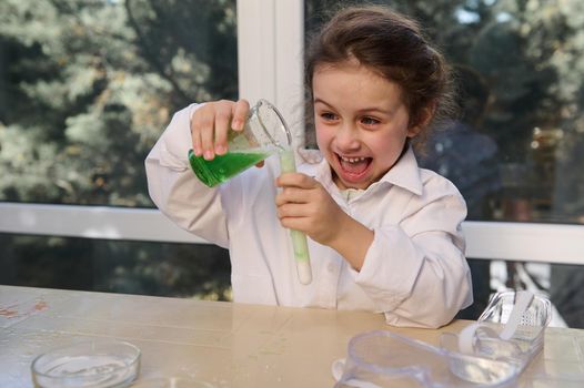 Mischievous little girl conducts chemical reactivity with citric acid soda, in school chemistry lab. Volcanic eruption