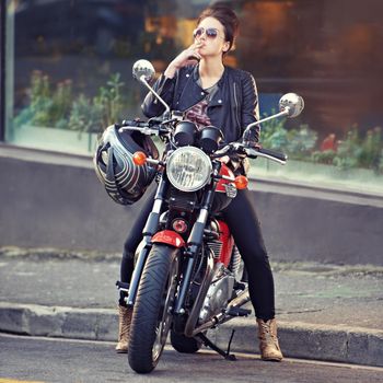 Stylish ride. a young female biker smoking a cigarette.