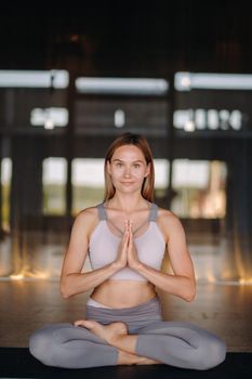 The girl does yoga. A woman in sports clothes does yoga exercises in the gym