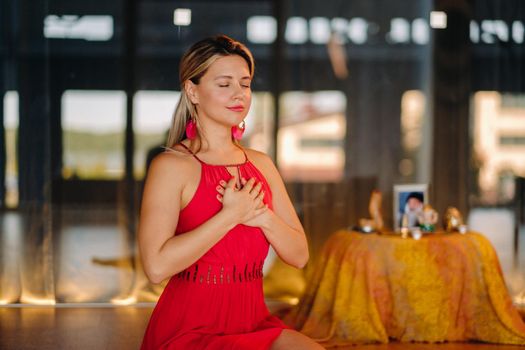 Meditation and concentration. a woman in a red dress, sitting on the floor with her eyes closed, is practicing medicine indoors. Peace and relaxation