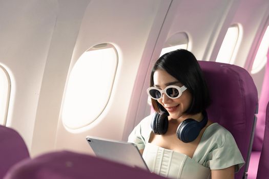 Passenger using tablet computer in airplane cabin during flight. watching series.