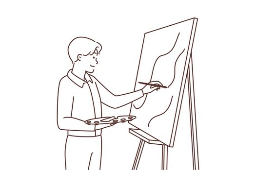 Young man drawing on easel