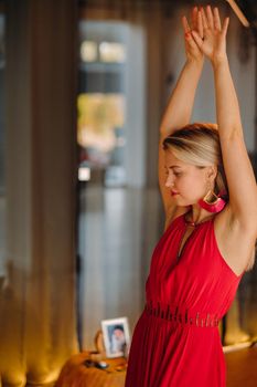 A girl in a red dress moves in a dance meditating indoors . Dynamic dance