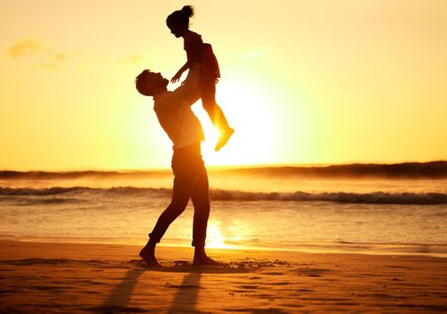 Father, girl and beach at sunset happy, silhouette of man and child together play on sand. Parent, ocean and sun, rising or setting over the horizon in nature, on vacation or family travel by the sea
