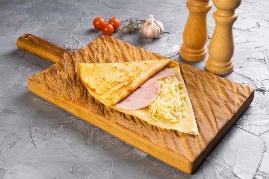 French crepe pancakes stuffed ham and cheese on cutting board