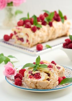 Baked meringue roll with cream and fresh red raspberry, white background