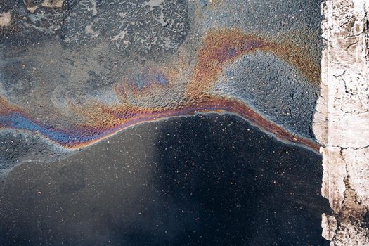 Gasoline spill on asphalt in a car park as a texture or background