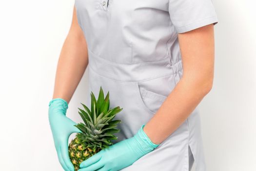 Female doctor beautician with pineapple. Concept of epilation or depilation and intimate hygiene.