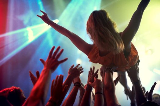 Crowd surfing. A young girl crowd surfing as a band plays one of her favourite songs.