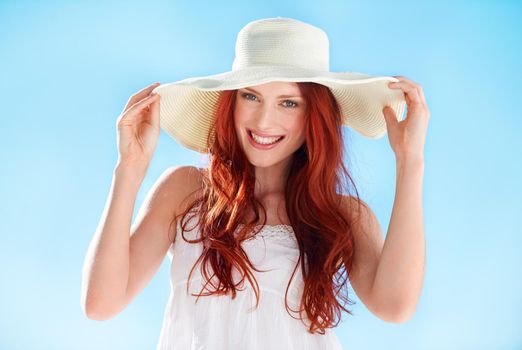 Protecting her delicate skin. A gorgeous young redheaded woman wearing a sunhat outside.