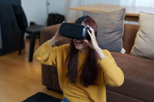 portrait of a young Asian woman using virtual reality simulator headset at home