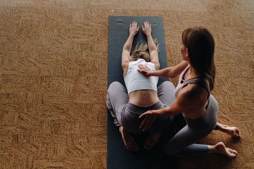 Yoga exercises. A personal trainer teaches a woman yoga classes in the gym