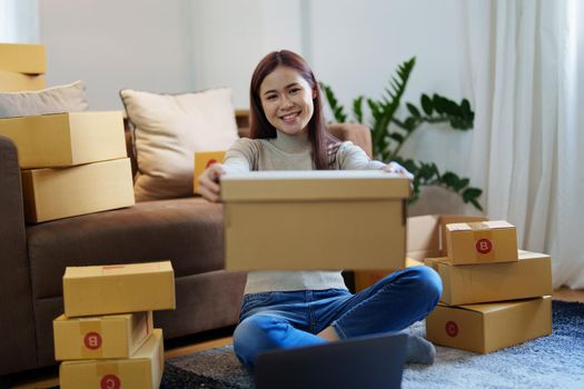 Portrait of a small startup Asian female entrepreneur SME owner picking up product before packing it in an inner box with a customer. Online Business Ideas and Freelance