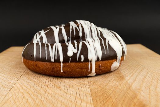 bun covered with chocolate, on a wooden board