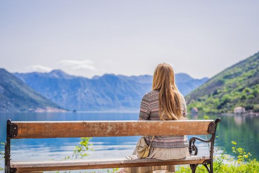 A woman sits on a bench and admires the view of the Bay of Kotor. Montenegro