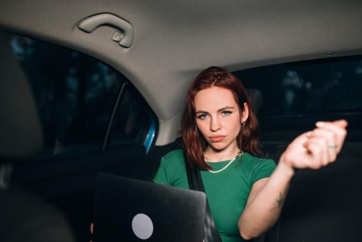 Beautiful woman is using laptop while sitting on back seat