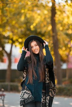 Stylish woman in poncho and hat enjoys autumn's park