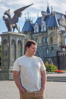 A man on the background of a Gothic-style castle. The territory of the tourist complex