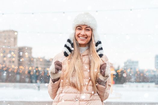 Happy winter time in big city charming girl standing street dressed funny fluffy hat. Enjoying snowfall, expressing positivity, smiling to camera