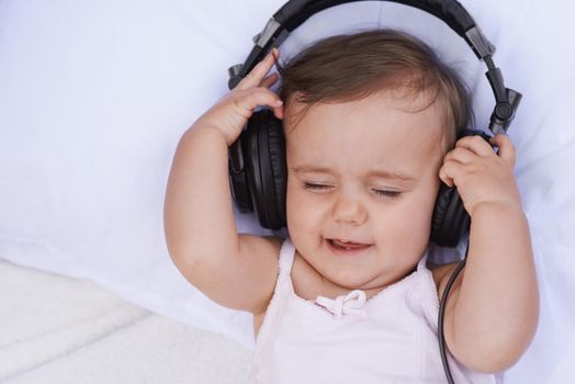 Listening to lullabies. A cute young baby girl listening to music on headphones.