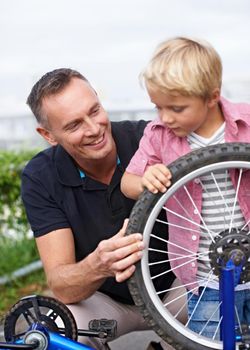 Father and son bonding. A handsome father showing his son the different parts of a bike.