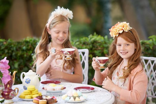 Having a make-believe tea party. Two young girls having a tea party in the backyard.