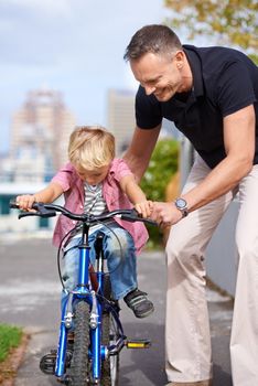 His first bike ride. A father teaching his young son to ride a bike.