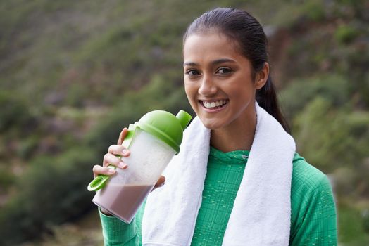 Staying healthy. A young ethnic woman drinking a sports drink outdoors