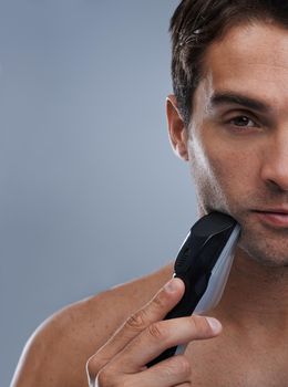 Modern day metrosexual. A young man shaving with an electric razor.