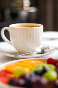 Breakfast and luxury, cup of coffee with milk and fruit platter on the served table for hospitality and gastronomy