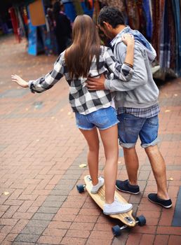 Getting in on his hobby. a young man teaching his girlfriend how to skateboard.